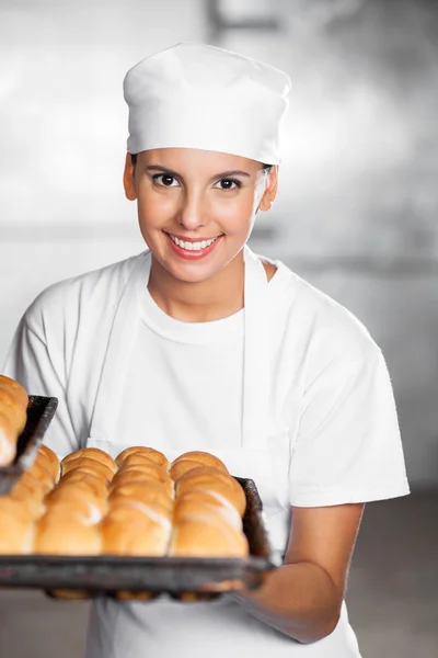 Όμορφη γυναίκα, που χαμογελά κρατώντας ψωμί δίσκο στο φούρνο — Φωτογραφία Αρχείου