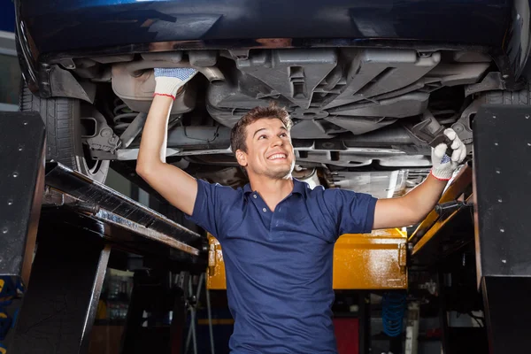 Mecánico examinando debajo del coche levantado — Foto de Stock