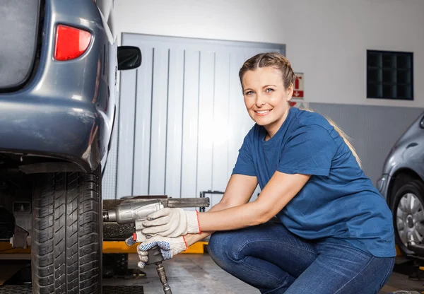 Pneu de fixação mecânico feminino sorridente com chave pneumática — Fotografia de Stock