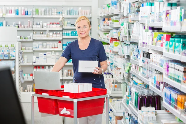 Farmacêutico sorridente atualizando estoque no laptop na farmácia — Fotografia de Stock