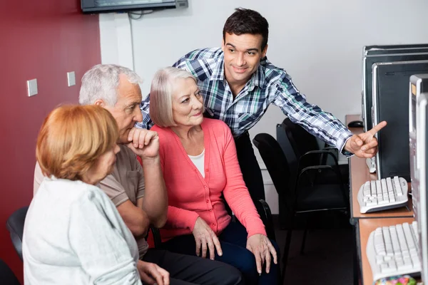 Lärare hjälpa seniora elever att använda dator på Class — Stockfoto