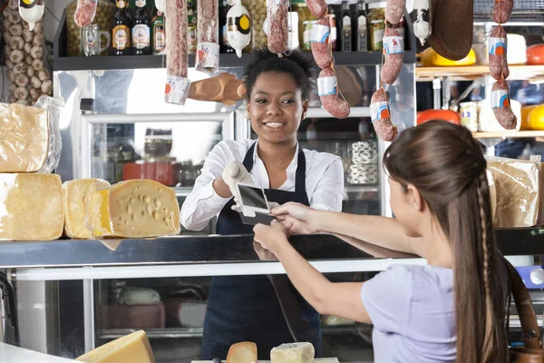 Saleswoman acceptant le paiement par carte de crédit à la fromagerie — Photo