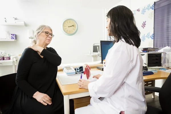 Patient souffrant de douleur à l'épaule tout en regardant le médecin — Photo