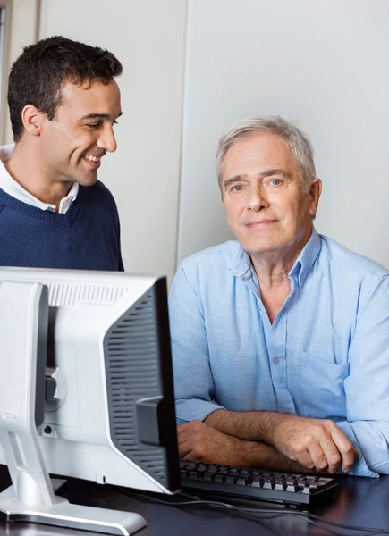 Uomo anziano con insegnante maschio in classe di computer — Foto Stock