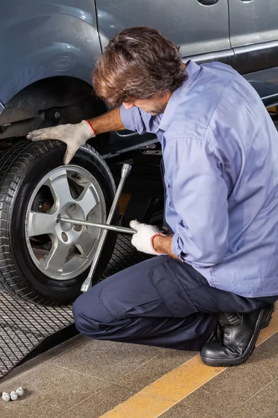 Pneu mecânico do carro da fixação com chave da borda na garagem — Fotografia de Stock