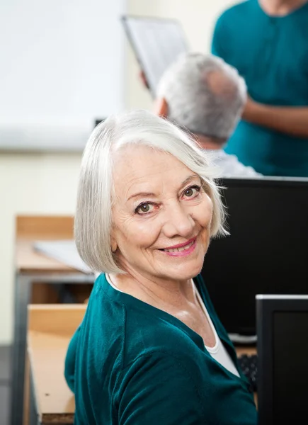 Mujer mayor feliz en el escritorio en la clase de informática — Foto de Stock