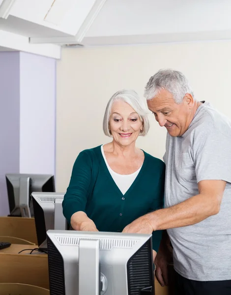 Glada Senior människor pekar på datorskärmen i klassrummet — Stockfoto