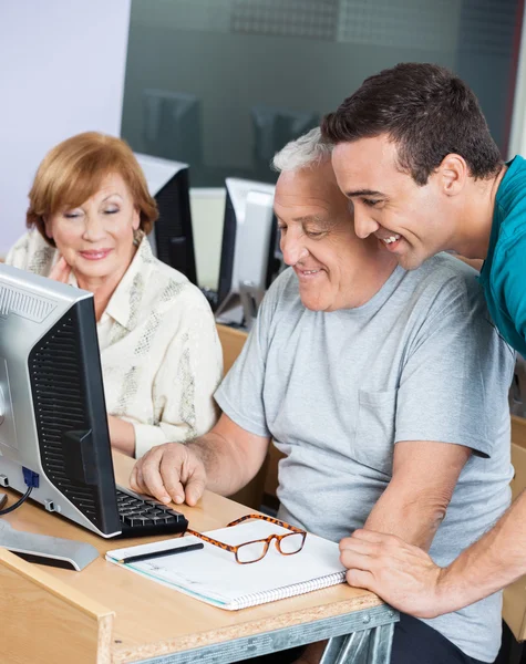 Tutor Assistere gli studenti anziani nell'utilizzo del computer in aula — Foto Stock