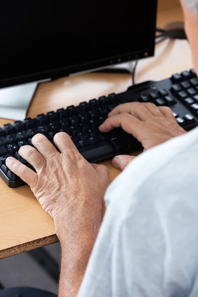 Senior benutzt Computer am Schreibtisch im Klassenzimmer — Stockfoto
