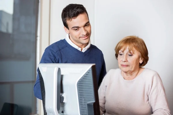 Glad lärare att hjälpa seniore elev i datorn klass — Stockfoto