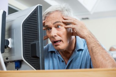 Stressed Senior Man Looking At Computer Monitor clipart