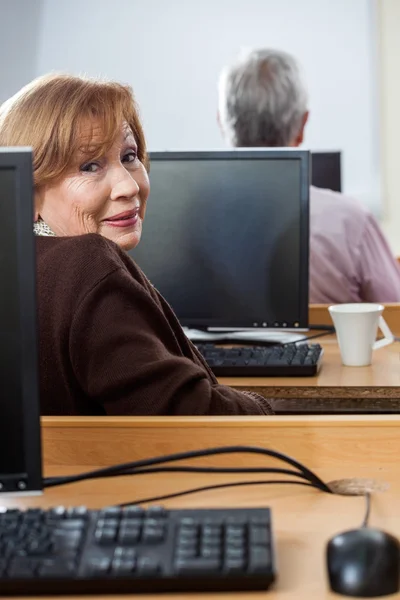 コンピューターのクラスに座っている年配の女性の笑顔のポートレート — ストック写真