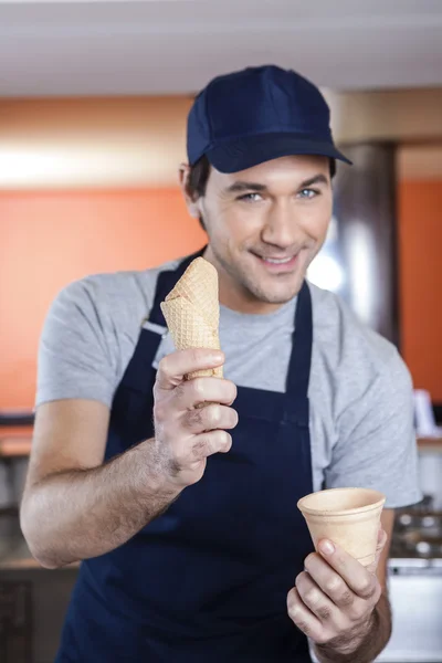 Camarero seguro eligiendo entre la taza y el cono en la tienda — Foto de Stock