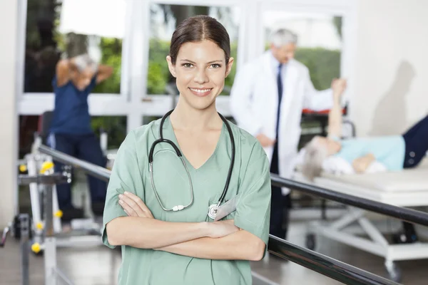 Leende kvinna sjukgymnast står i Rehab Center — Stockfoto