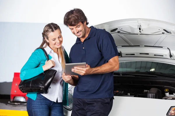 Клієнт і технік використовуючи цифровий планшет на автомобілі — стокове фото