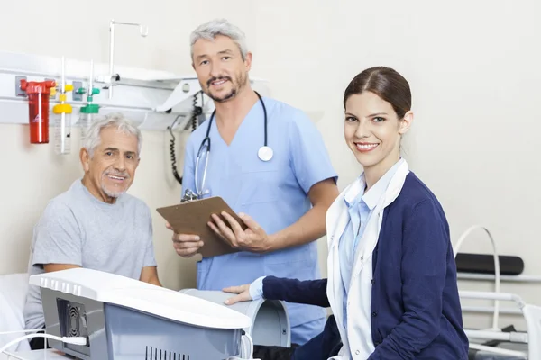 Fisioterapeutas sonrientes y paciente en la clínica de rehabilitación — Foto de Stock