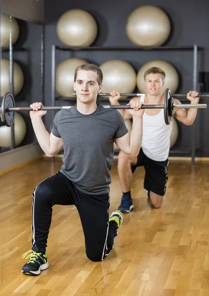 Amigos masculinos levantando barra en el gimnasio — Foto de Stock