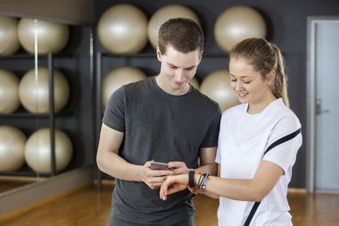 Arkadaşlar cep telefonu ve takılabilir spor salonunda kullanarak
