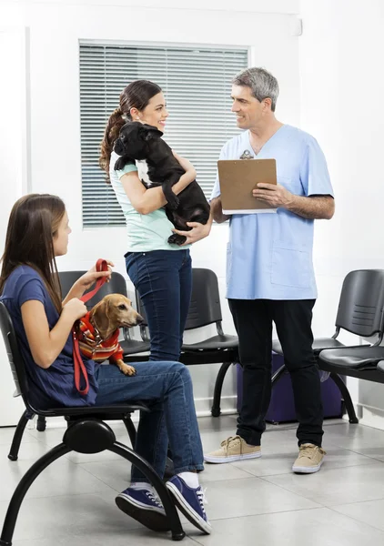 Enfermera sosteniendo portapapeles mientras los dueños de mascotas lo miran — Foto de Stock