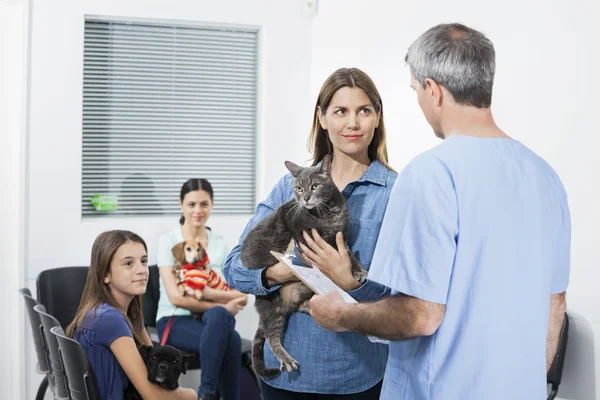 Donna che porta gatto mentre guarda infermiera in clinica — Foto Stock