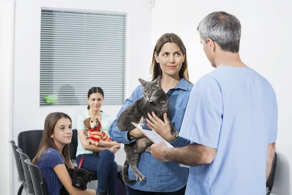 Mulher carregando gato enquanto olha para enfermeira na clínica — Fotografia de Stock