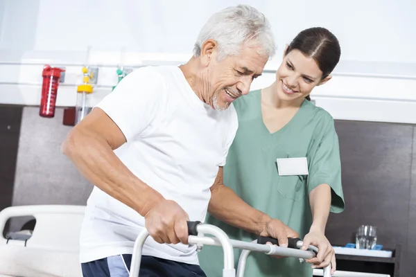 Krankenschwester betrachtet Patientin mit Rollator im Reha-Zentrum — Stockfoto