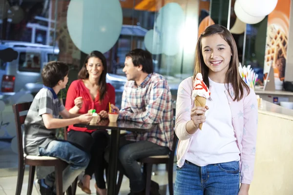 Leende flicka håller Vanilla Ice Cream Cone i salongen — Stockfoto