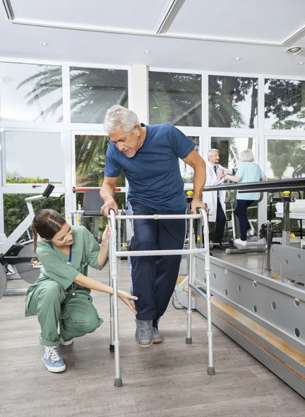 Female Nurse Helping Senior Patient With Walker In Fitness Studi — Stock Photo, Image