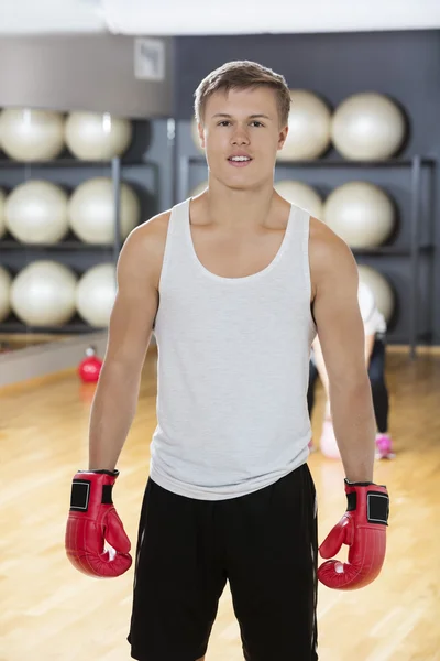 Uomo sicuro di sé che indossa guanti da boxe in palestra — Foto Stock