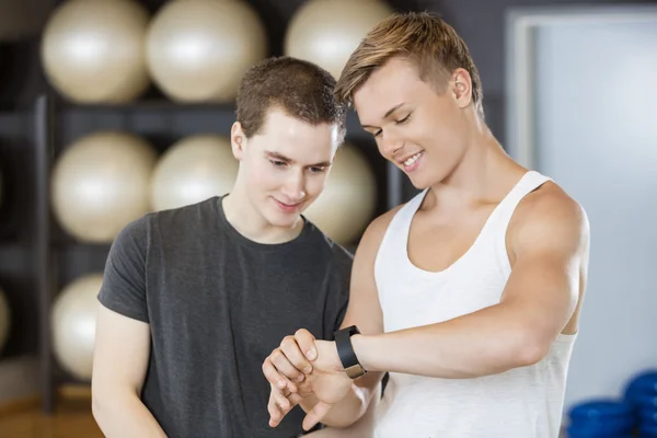 Amis masculins regardant le podomètre dans la salle de gym — Photo