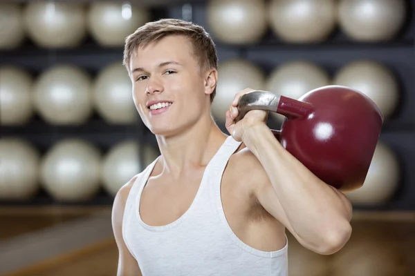 Hombre atractivo haciendo ejercicio con Kettlebell en el gimnasio — Foto de Stock
