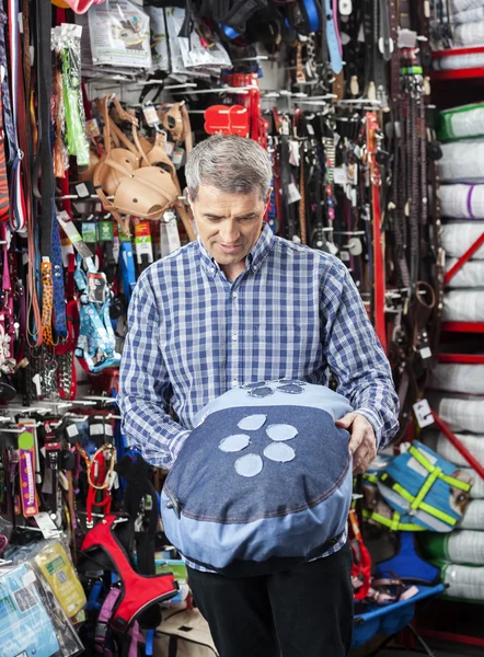 Homme examinant le coussin pour animaux en magasin — Photo