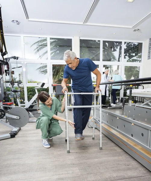 Female Nurse Assisting Senior Patient With Walker In Fitness Stu — Stock Photo, Image