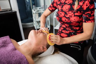 Sünger ile müşteriler yüz temizliğinde güzellik uzmanı