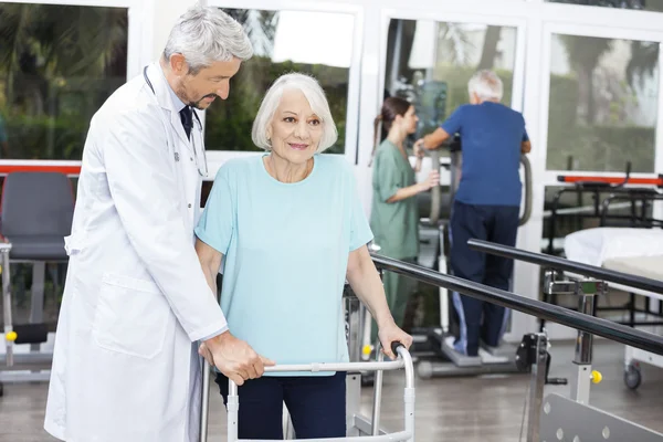 Médico auxiliar paciente sênior com Walker no estúdio de fitness — Fotografia de Stock