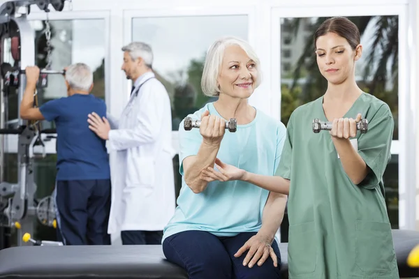 Verpleegkundige opdrachtgever Senior vrouw uitoefenend met halter — Stockfoto