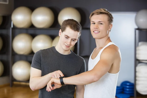 Hombre mostrando podómetro a amigo en el gimnasio — Foto de Stock