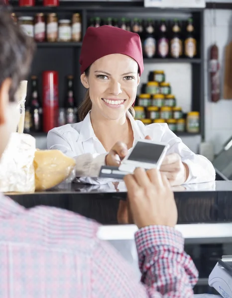 Vendedora aceptando el pago del cliente en la tienda de quesos — Foto de Stock