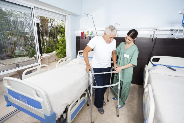 Verpleegkundige helpen mannelijke patiënt gebruik van Walker op Rehab Center — Stockfoto