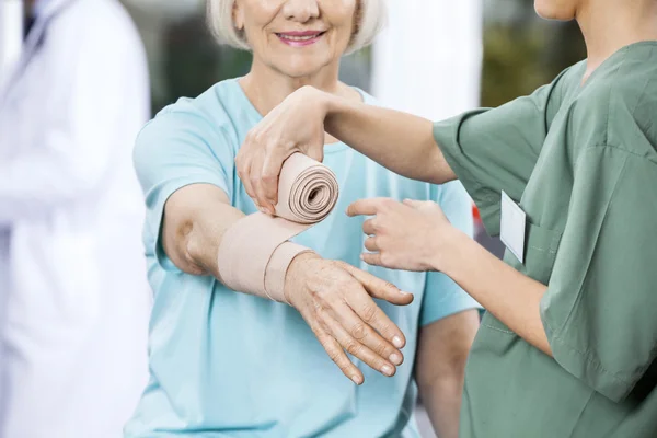 Enfermeira Colocando Crepe Bandage na mão de pacientes no centro de reabilitação — Fotografia de Stock