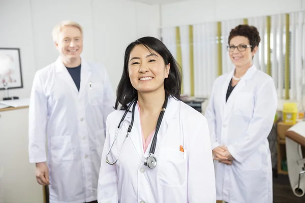 Felice medico femminile in piedi con i colleghi — Foto Stock