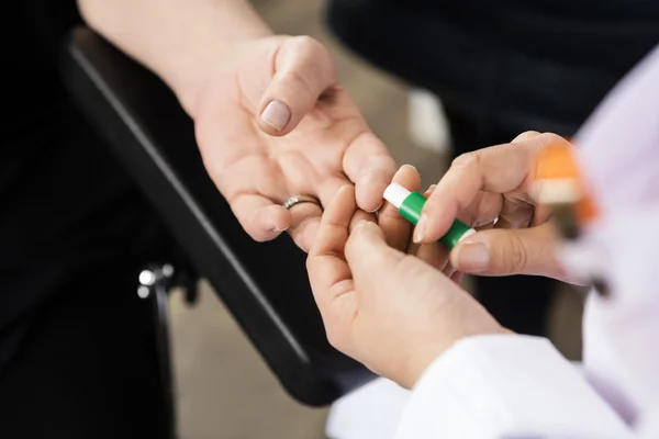 Médico usando herramienta en pacientes dedo para análisis de sangre en el hospital — Foto de Stock