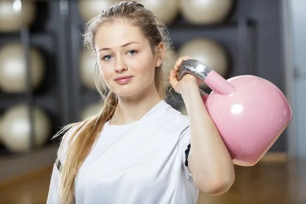 Attraente giovane donna sollevamento kettlebell in palestra — Foto Stock