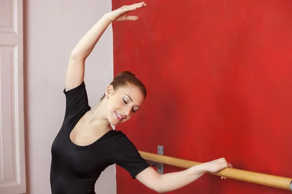 Ballerino Stretching Hand At Barre In Studio — Foto Stock