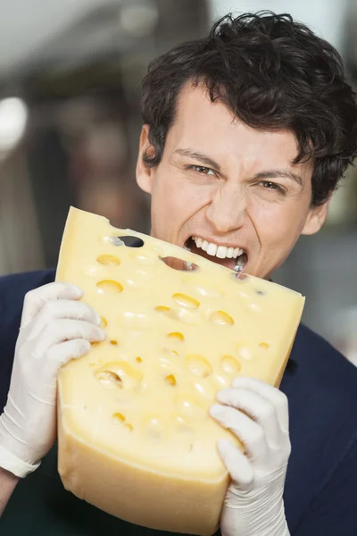 Jeune vendeur mangeant du fromage en magasin — Photo