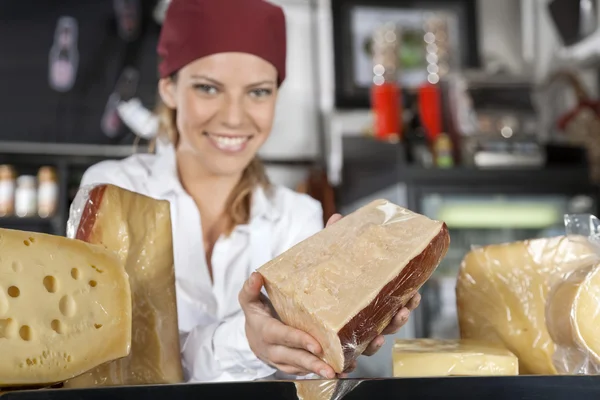 Vendedora mostrando queijo na mercearia — Fotografia de Stock