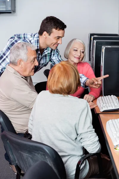 Insegnante Assistere gli studenti anziani nell'utilizzo del computer in aula — Foto Stock