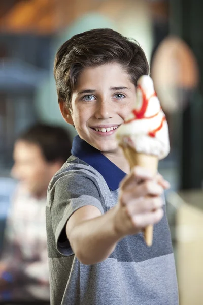 Menino mostrando delicioso sorvete com xarope de morango — Fotografia de Stock