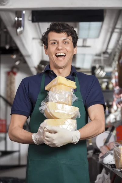 Jovem vendedor alegre levando queijo na loja — Fotografia de Stock