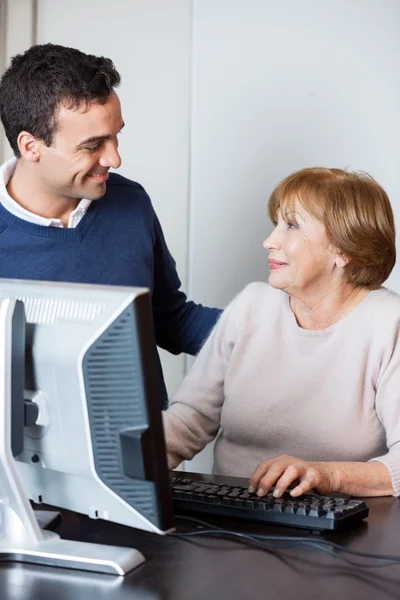 Lärare hjälpa seniore elev i datorn klass — Stockfoto